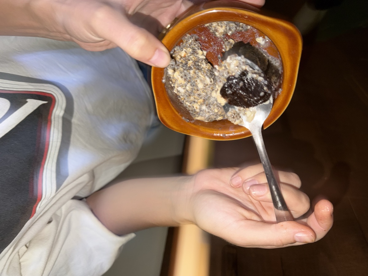 a friend holding a small container of sludge with a spoon